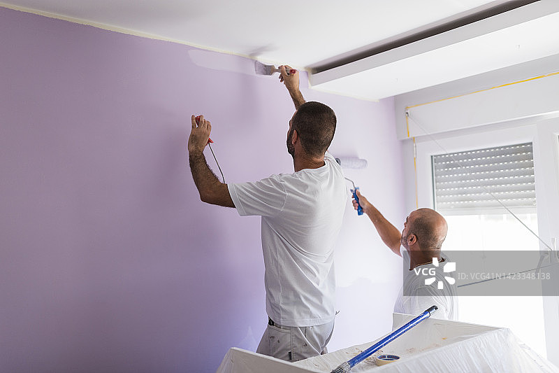 家庭油漆工在把房间漆成紫色时组成一个团队图片素材