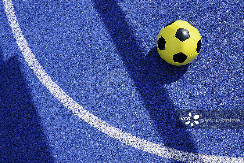 五颜六色的运动场背景。俯视图浅蓝色场地橡胶地面与白色线，阴影从足球球门网和黄色足球晴天户外图片素材