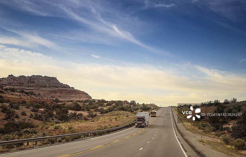 美国犹他州，一辆半挂车后面跟着一辆校车行驶在一条空旷的高速公路上图片素材