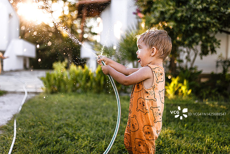 小男孩给花园浇水，玩得很开心图片素材