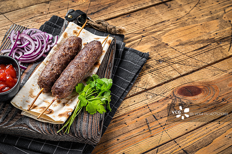 传统的中东烤肉串，用碎牛肉和羊肉串在烤串上，配上大饼和洋葱。木制背景。前视图。本空间图片素材