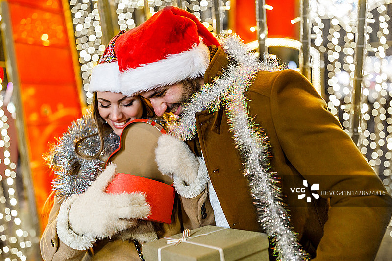 一对有魅力的夫妇正在街上享受圣诞夜，分享礼物。图片素材