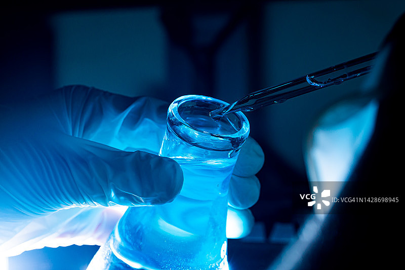 蓝色玻璃试管，亚洲女科学家与试管做研究的临床实验室的科学，化学，技术，生物和人的概念。图片素材