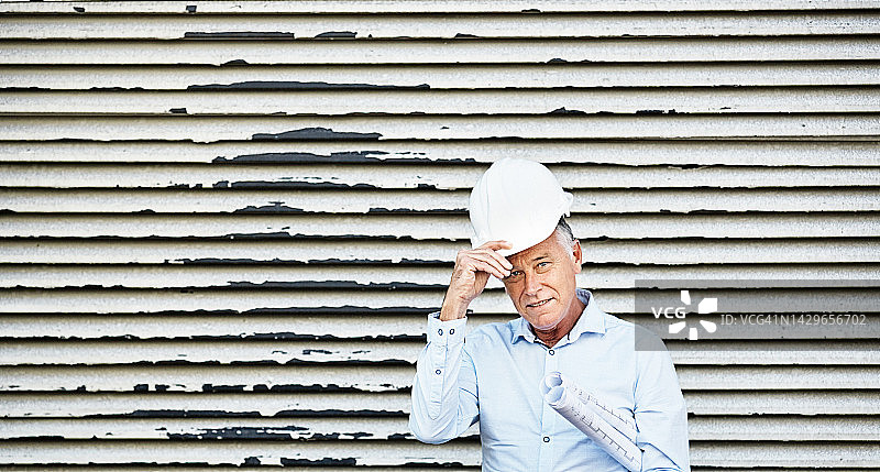 英俊的中年男子，戴着安全帽，计划着:建筑老板，建筑师或土木工程师图片素材