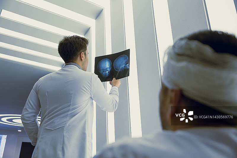 年轻的医生正在看病人头骨的x光片图片素材