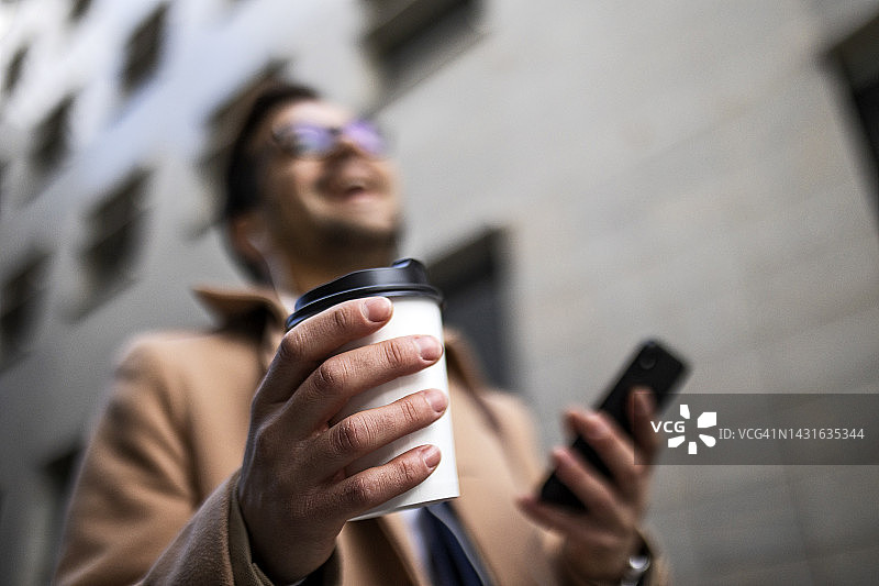 商人带着手机在街上，专注于咖啡图片素材