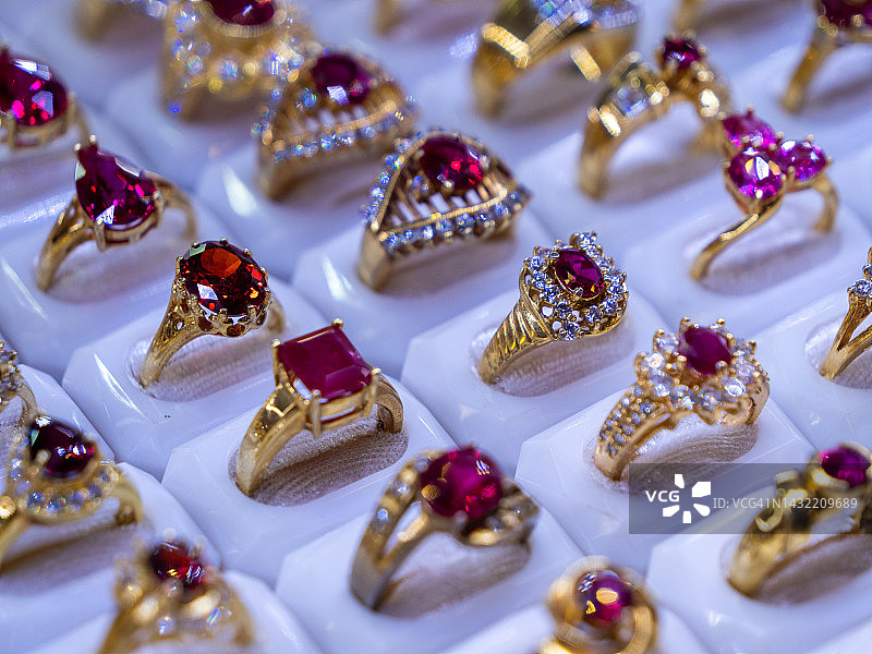 红宝石和粉色黄玉彩色宝石套装戒指排列在一排珠宝店设置。奢华的戒指展示，闪闪发光的宝石和钻石。高端奢侈品购物。图片素材
