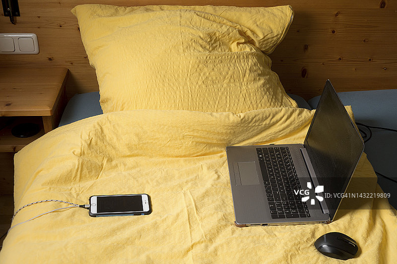 笔记本电脑，手机和羽绒被放在床上图片素材