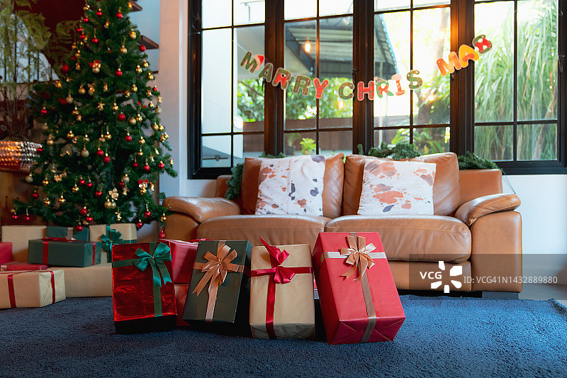 美丽的圣诞礼品盒在房间杉树附近的地板上。圣诞礼物灯和装饰图形插图图片素材
