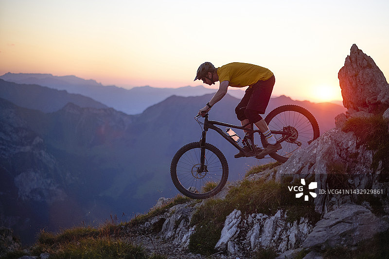 山地车骑手在日落时骑在岩石小道上图片素材