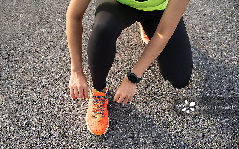 跑步鞋。女子系鞋带。特写的女性运动健身跑步者准备慢跑户外森林小路在夏末或秋天。慢跑姑娘锻炼动机健康健美。图片素材