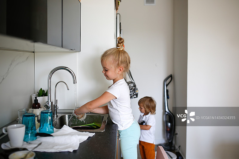 女孩洗菜。白人小女孩早餐后在厨房打扫和洗碗图片素材