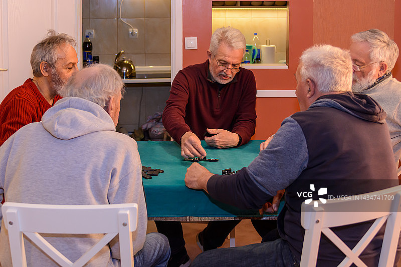 活跃的老年人正在家里玩多米诺骨牌游戏。图片素材