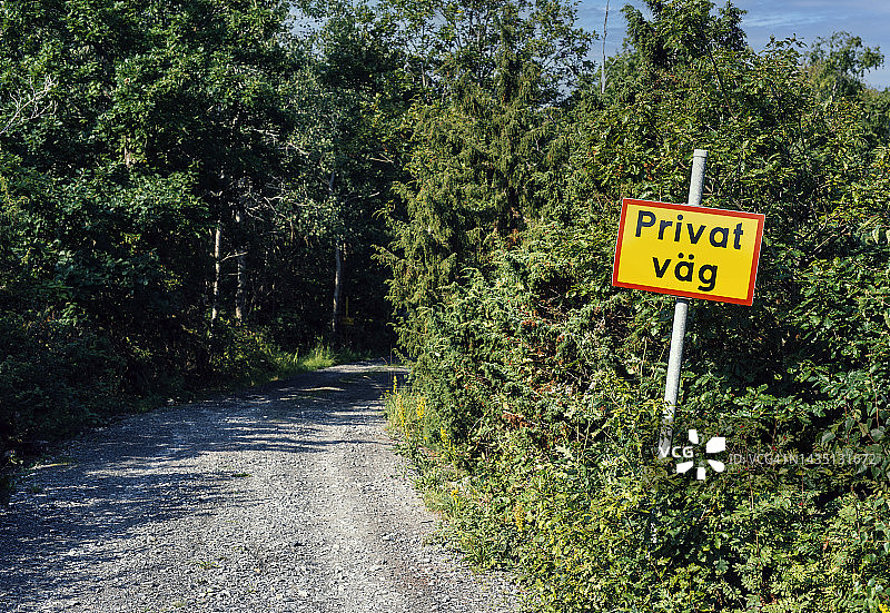 在一条未铺设的砾石小路的开头，有一个牌子，上面写着瑞典语Privatväg，翻译过来就是私人道路图片素材