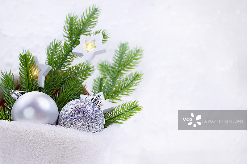 银色闪亮的球与杉木树枝和星星灯在毛皮袋在白色背景。圣诞节,新年。本空间图片素材