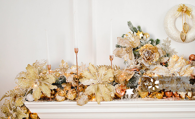 白色和金色的圣诞壁炉装饰，有蜡烛和花环图片素材
