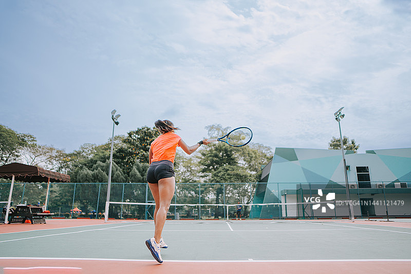 亚裔印度女网球运动员在教练指导下在网球场练习发球图片素材