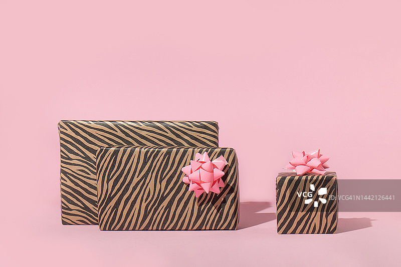 圣诞创意布局上的礼物在柔和的粉色背景。八九十年代的审美时尚假日概念。迷你新年派对的想法。图片素材