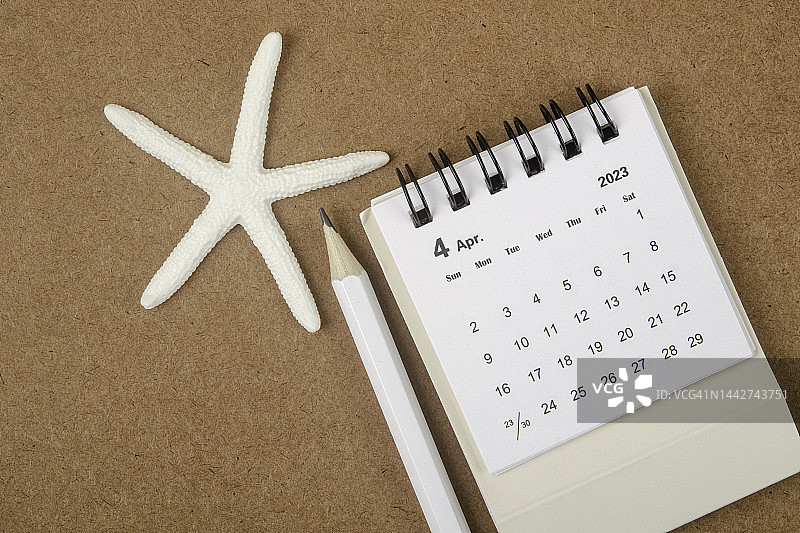 日历桌2023:4月是组织者用海星和棕色纸背景的白铅笔做计划和截止日期的月份。图片素材