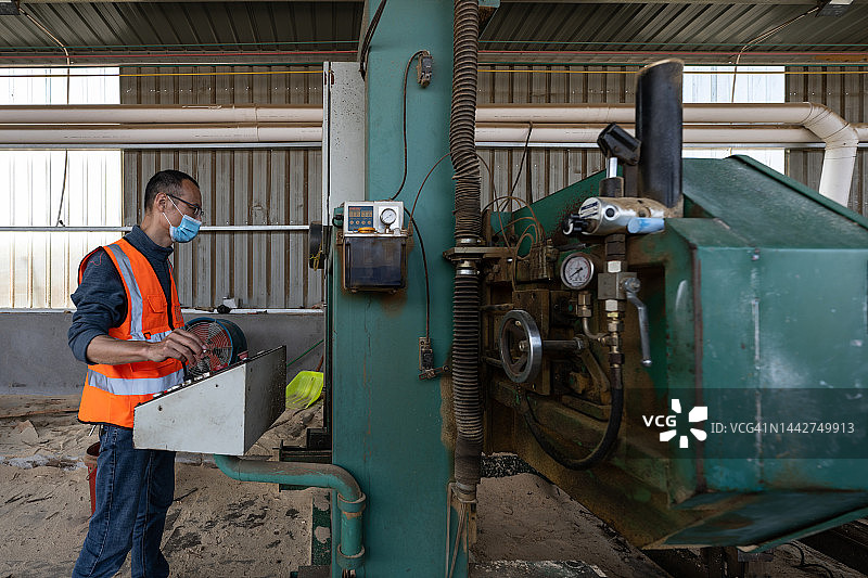 一位亚洲男性工人在一家木材加工厂工作图片素材