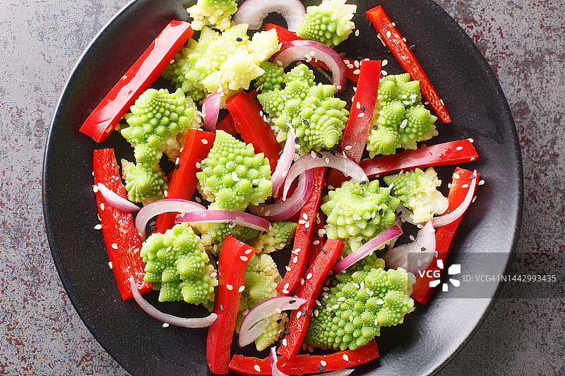 有机饮食新鲜沙拉罗马花椰菜，甜椒和红洋葱撒芝麻在盘子里特写。水平俯视图图片素材