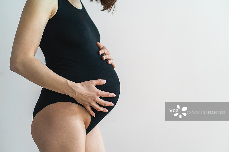 怀孕期间胃痛，背痛。孕妇身体的中段，双手放在腹部图片素材