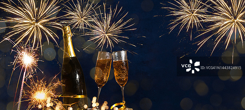 2023年新年快乐庆祝节日贺卡背景横幅-香槟或起泡酒瓶和敬酒杯，火花和烟花在晚上图片素材