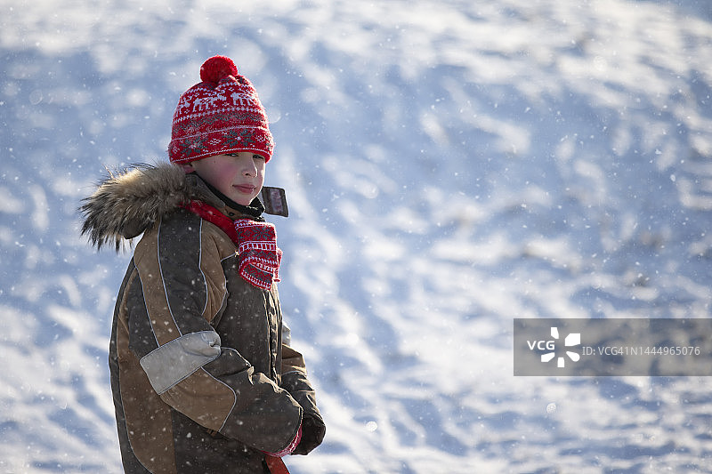 一个男孩穿着暖和的衣服在冬天散步。图片素材