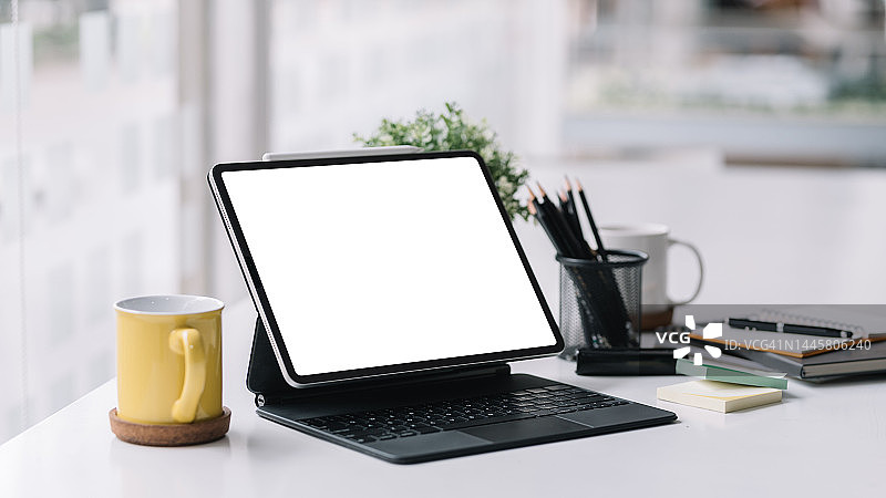 平板电脑与键盘空白白色屏幕放在办公桌上。模拟。图片素材