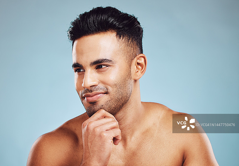 男性美容，护肤和健康的印度模特思考皮肤病学，健康和健康的蓝色工作室背景。男士面带微笑，面部排毒及自我护理后肌肤健康图片素材