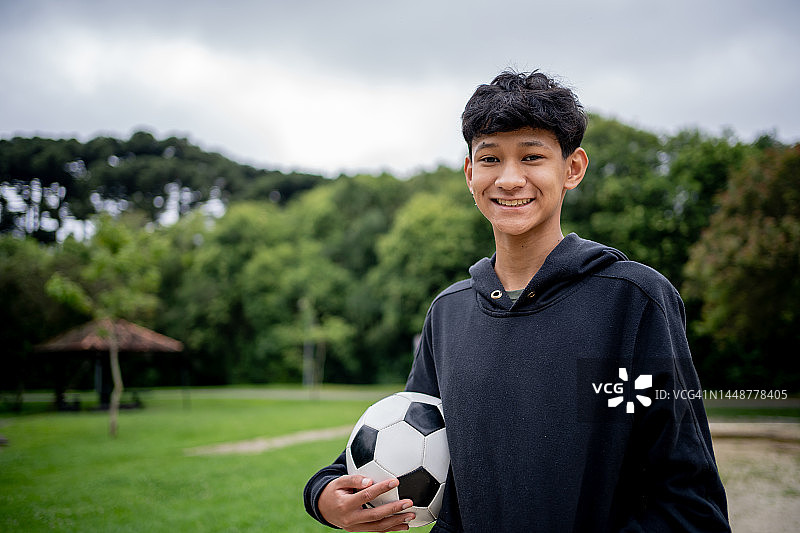 亚洲男孩在公园手拿足球的肖像图片素材