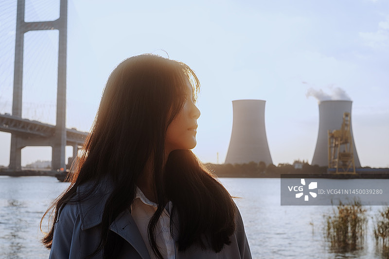 自信的亚洲妇女站在冷却塔和桥附近图片素材