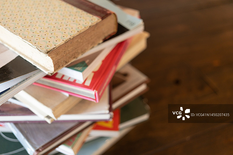 将书籍或教科书堆放在房间的木桌上。图片素材