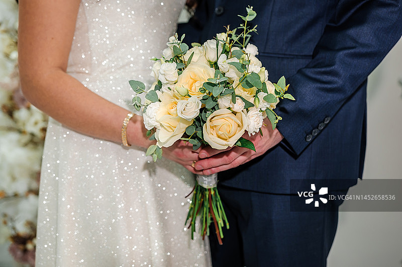 新郎牵着新娘的手，背景是五彩缤纷的婚礼花束图片素材