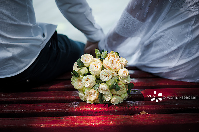 新郎牵着新娘的手，背景是五彩缤纷的婚礼花束图片素材