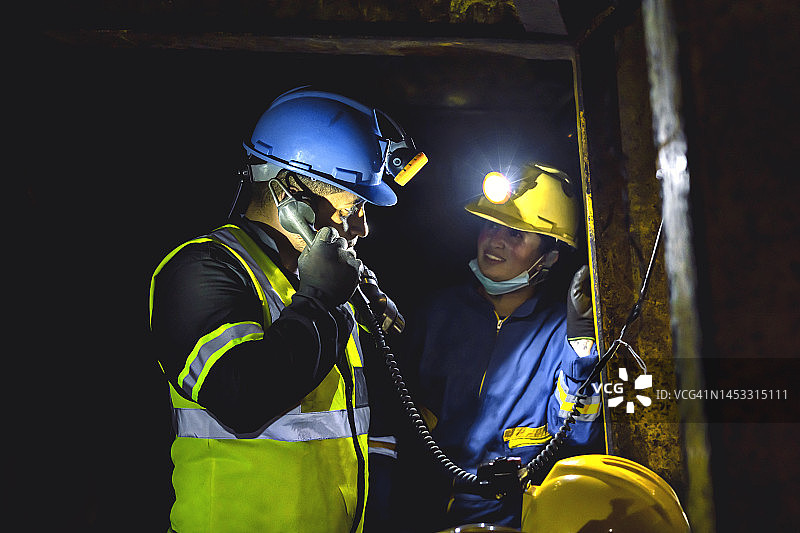 在地铁矿井里，矿工们一边工作一边用基因电话打电话。图片素材