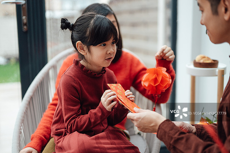 可爱的亚洲小女孩在中国新年期间收到父亲的红口袋图片素材