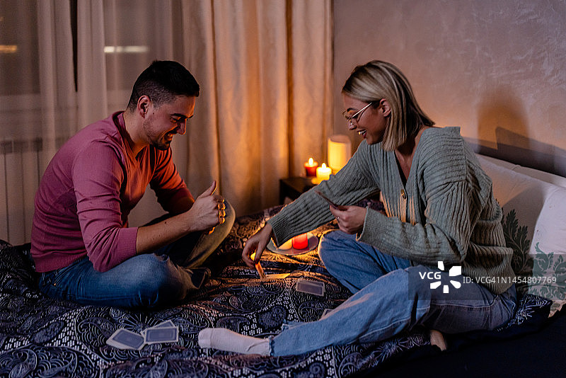 在一次电力危机中，一个年轻的男人和女人坐在家里打牌。图片素材