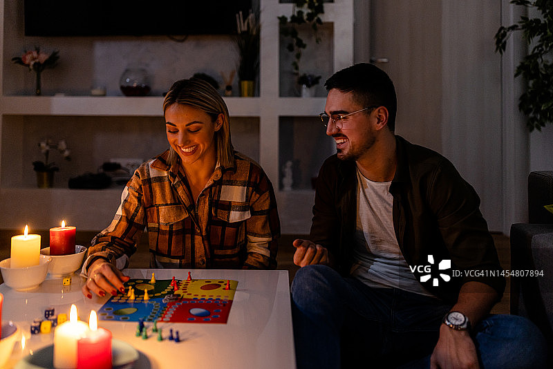 在一次精力危机中，一个男人和一个女人在黑暗中点着蜡烛玩卢多游戏。图片素材