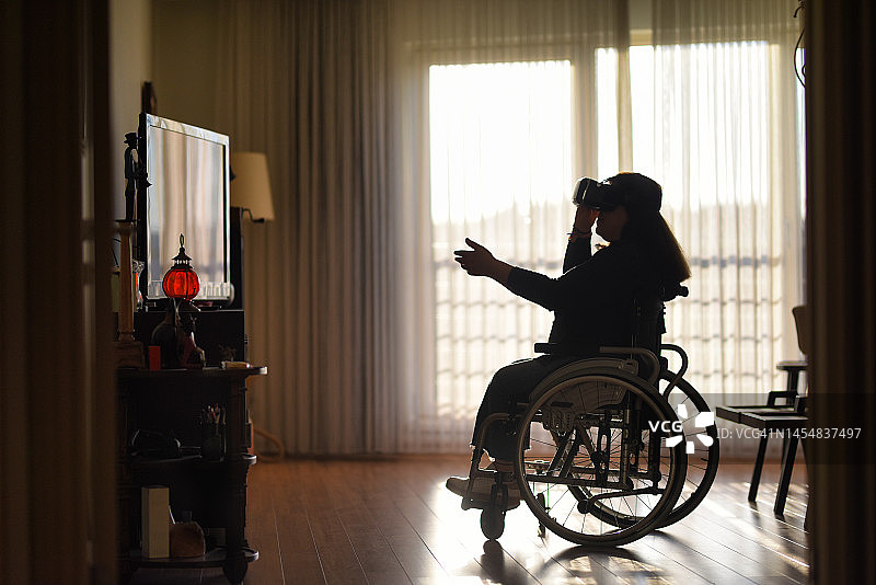 坐在轮椅上的妇女在家里使用vr眼镜图片素材