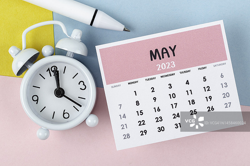 日历台2023:五月是组织者用闹钟和白笔在双色纸背景下计划和截止日期的月份。图片素材