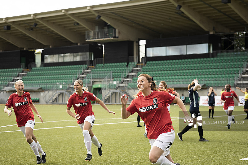 在体育场的足球比赛中，兴奋的女球员在进球后奔跑图片素材