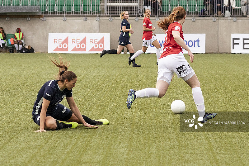 女子足球运动员在体育场比赛中铲倒对手时摔倒图片素材