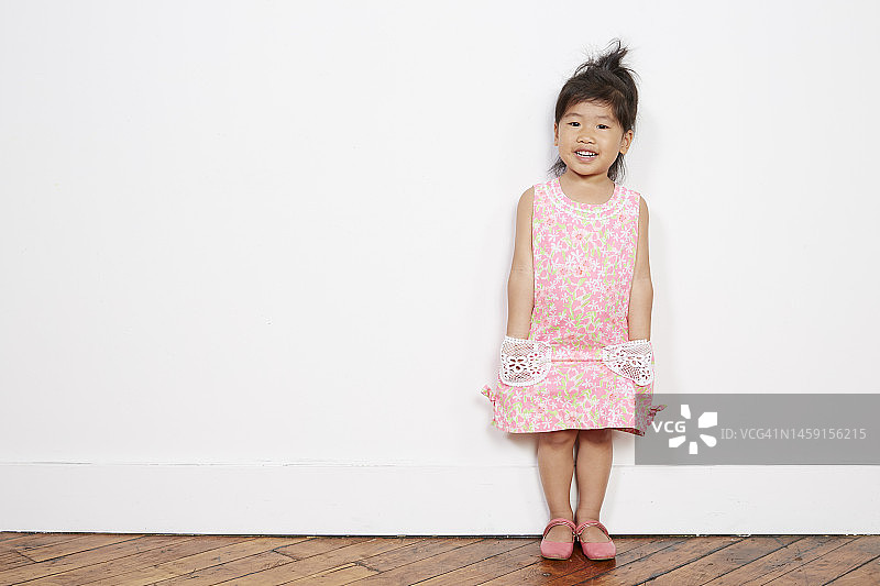 快乐的亚洲蹒跚学步的女孩在粉红色的花裙子图片素材