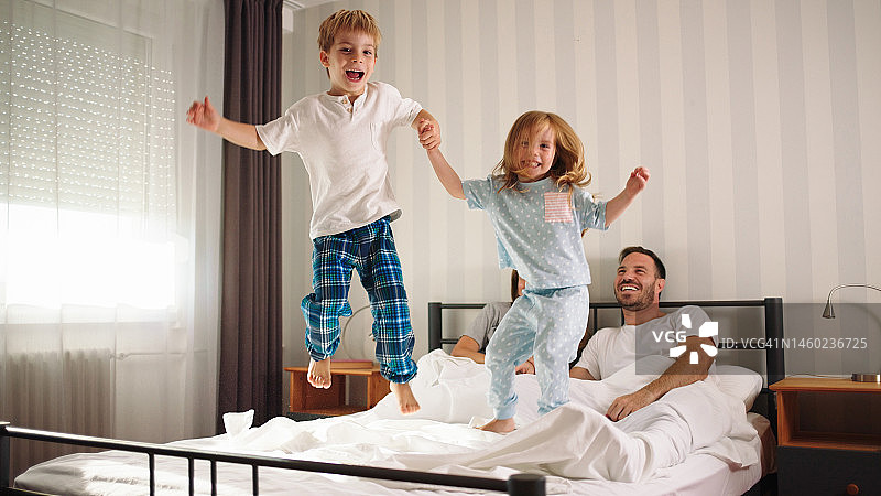 小弟弟和小妹妹在一个周末的清晨跳到父母的床上图片素材