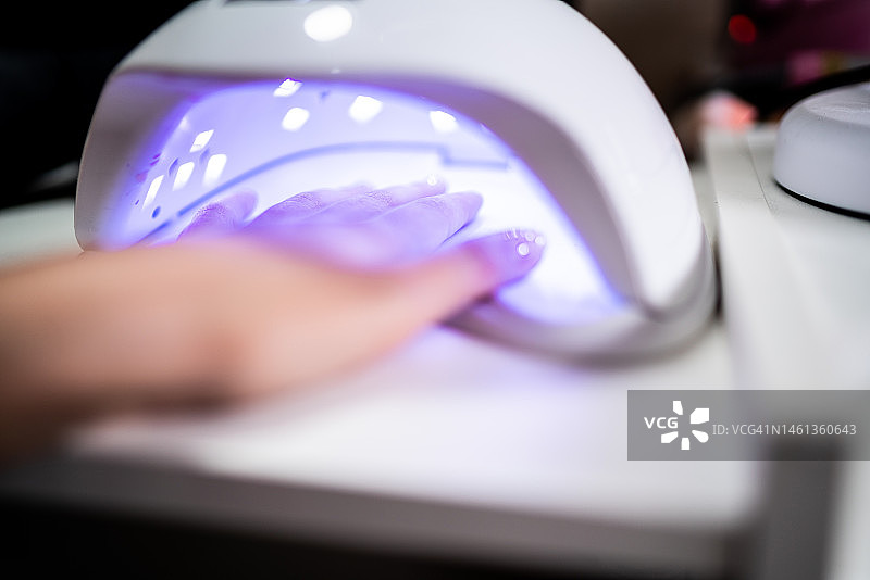 在美容院，一位女士的手伸进紫外线灯里做指甲图片素材