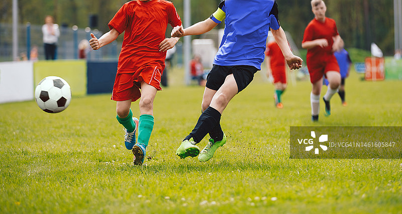 足球运动员决斗。青少年足球锦标赛比赛。在一场青少年级别比赛中，足球运动员们在草地上争夺足球图片素材