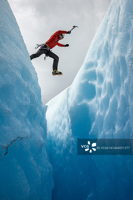 一名登山者跳过冰川大裂缝图片素材