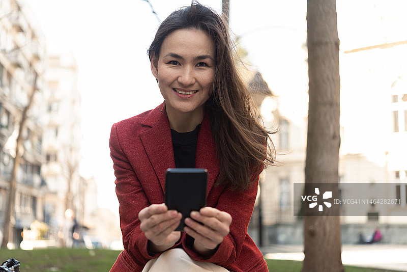 一名亚洲女性在城市中使用智能手机图片素材