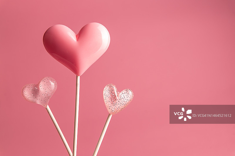 三颗粉色情人节心形棒棒糖放在空粉彩上图片素材
